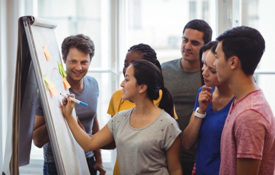 Business executive explaining her colleagues on whiteboard in office